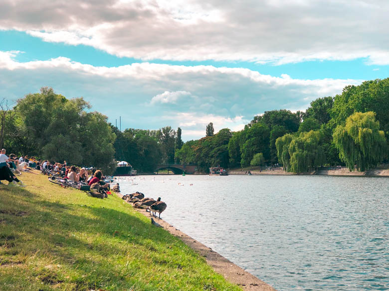 landwehr canal is a popular outdoor thing to do in berlin especially during coronavirus pandemic with people sitting on the grass overlooking the canal