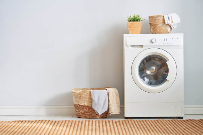 a white washing machine next to a wooden laundry basket