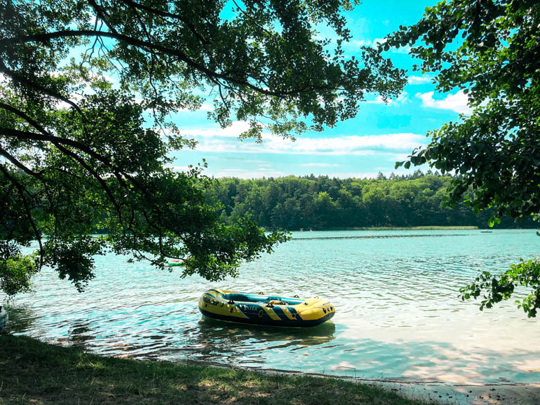 a rubber blue and yellow boat floats on the turquiose waters of liepnitzsee lake near berlin