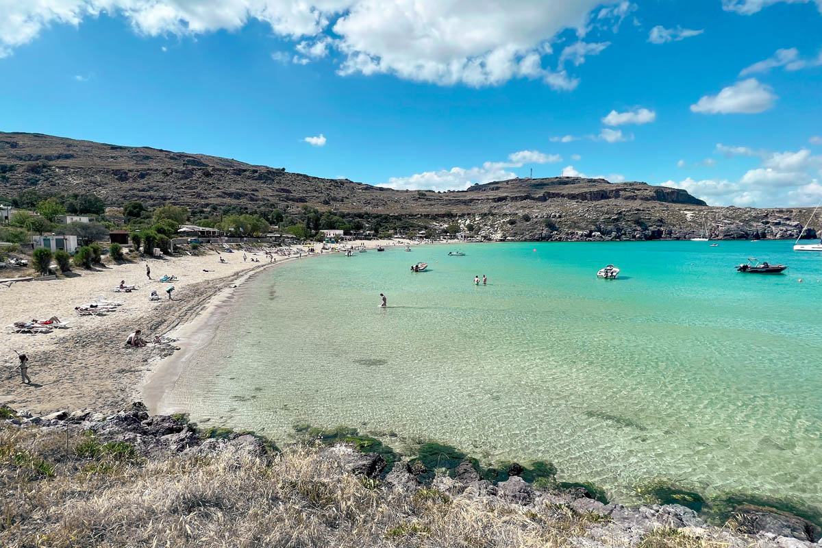 a view of white sandy lindos beach with shallow turquoise blue waters