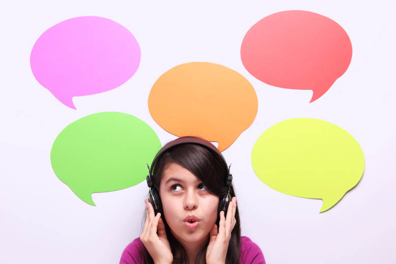 a girl with headphones on taking online language classes with five colorful speech bubbles behind her