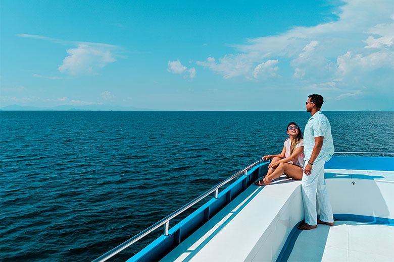 a couple standing on the bow of a liveaboard boat while admiring the Andam Sea as they sail towards the Similan Islands