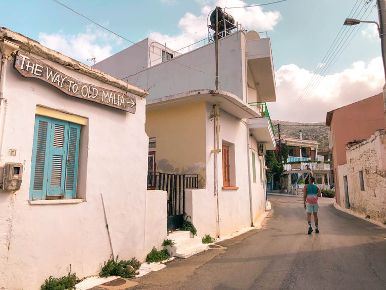 a view of malia with a sign that points to the way to old town malia on crete island greece