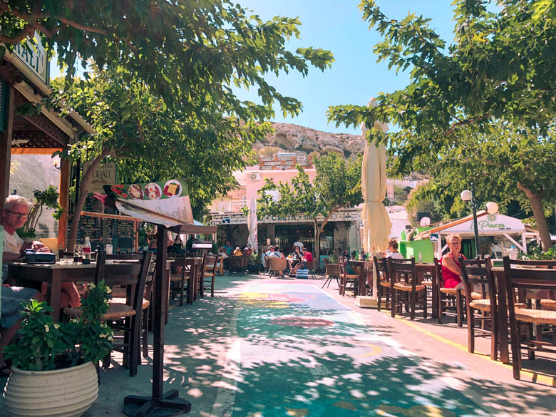 hipster town of matala in crete with street art painted on the road with restaurants lining the streets