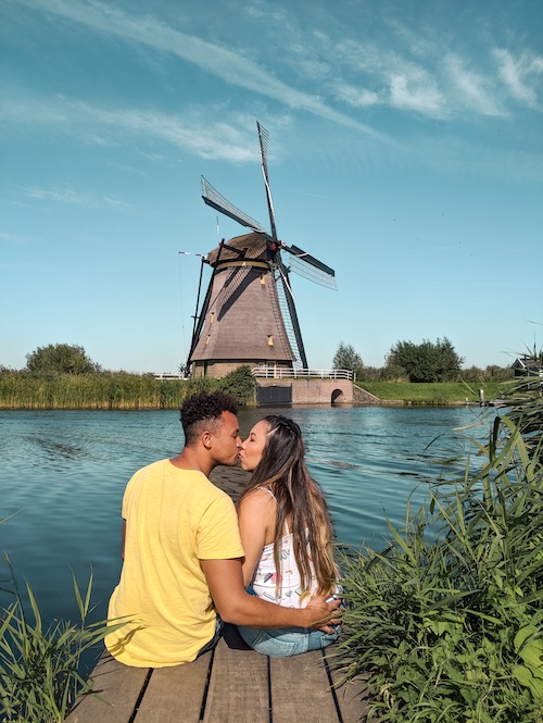 a couple kissing in front of a windmill in kinderdijk netherlands