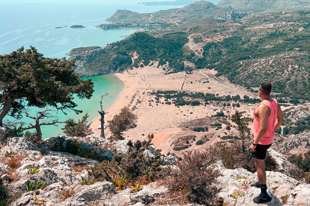 a man looking at tsambika beach from a high viewpoint