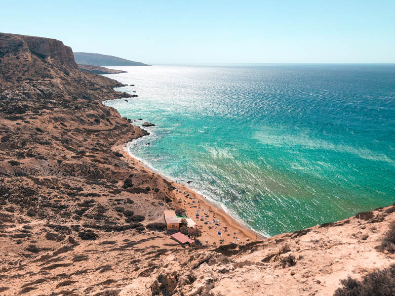 aerial view of red beach near matala in crete with its red sand, clear turquoise blue waters and stark cliffs surrounding it