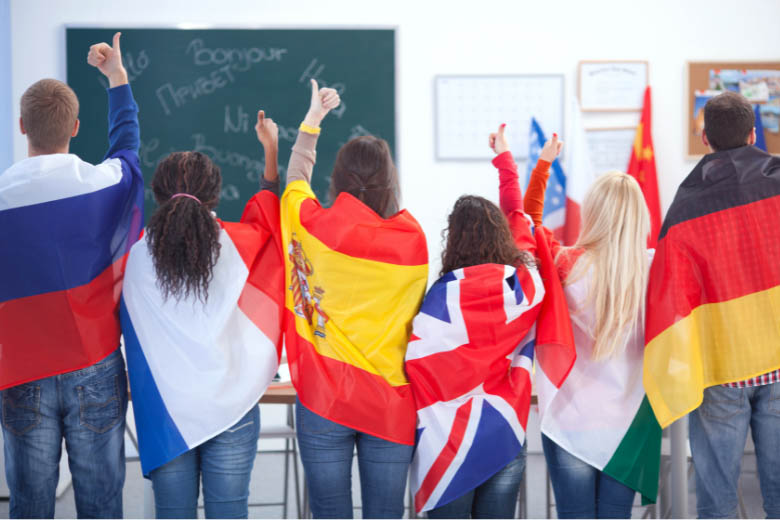 students standing in language classes wrapped in flags of different countries