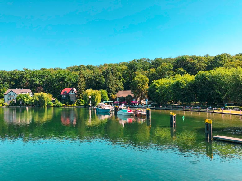 leisure yachts floating on top of a clear lake in Germany with houses and trees lining the edges at Schleuse Woltersdorf