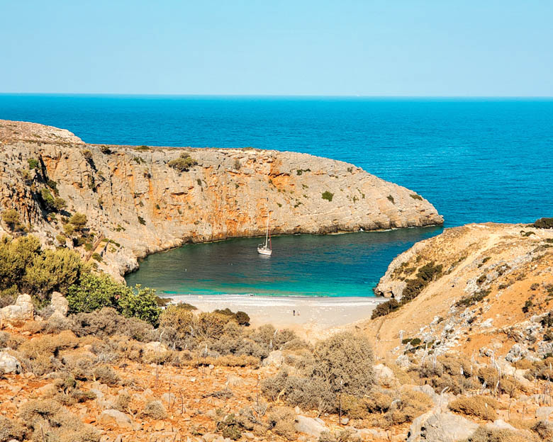 a view of a quiet, remote beach in crete from the top, surrounded by rocky cliffs and the clearest turquoise blue waters in greece