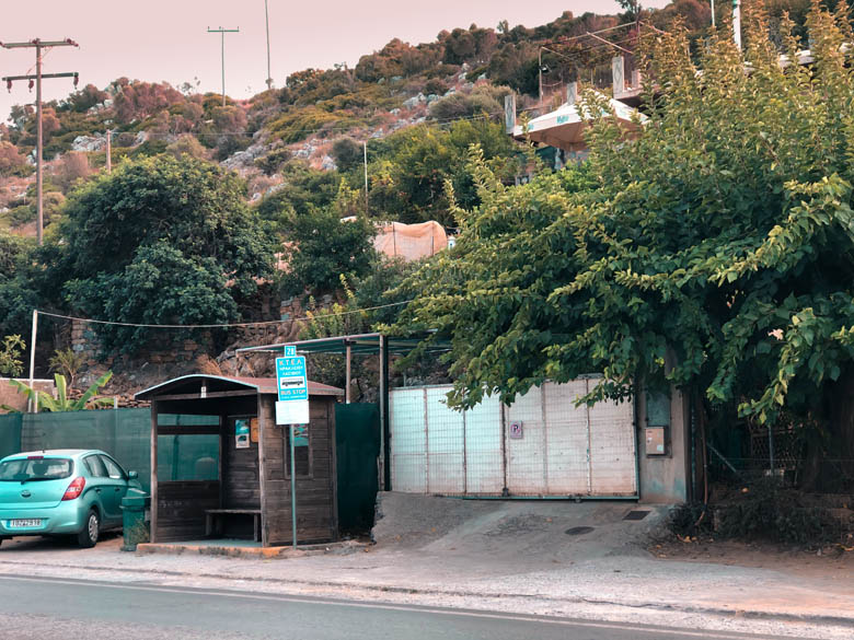 a small wooden hut on the side of the road is what bus stops look like in crete