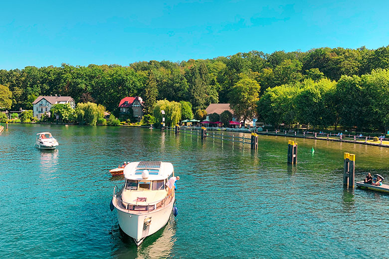 a sailing boat floating on flakensee lake near berlin with houses on the edge of the water