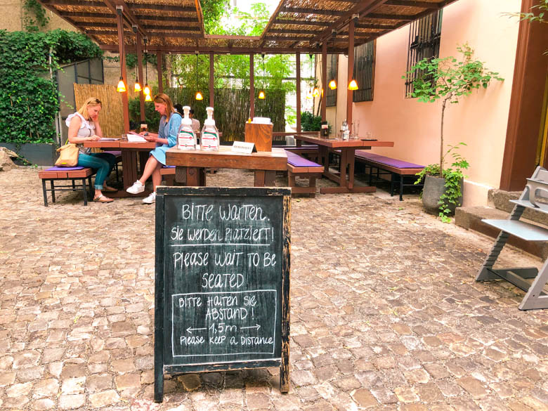 restaurant with outdoor seating in berlin mitte with please wait to be seated sign during coronavirus pandemic or covid