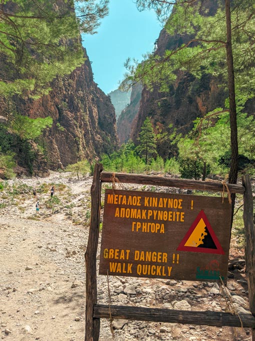 a warning sign along the european e4 hiking trail in crete asking hikers to beware of falling rocks