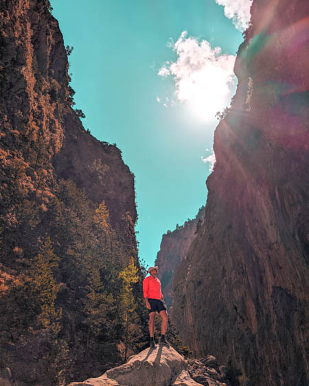 an instagram photo of a man standing on a rock at the bottom of samaria gorge