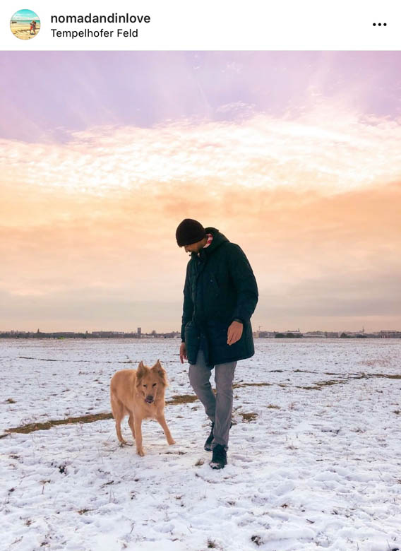 sunset photography at tempelhofer feld in berlin with a man walking a dog in the snow