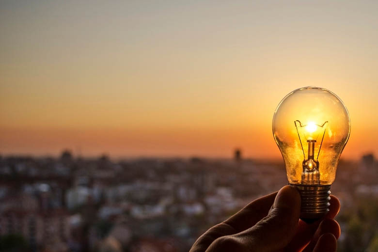 a glowing lightbulb held against the sunset 