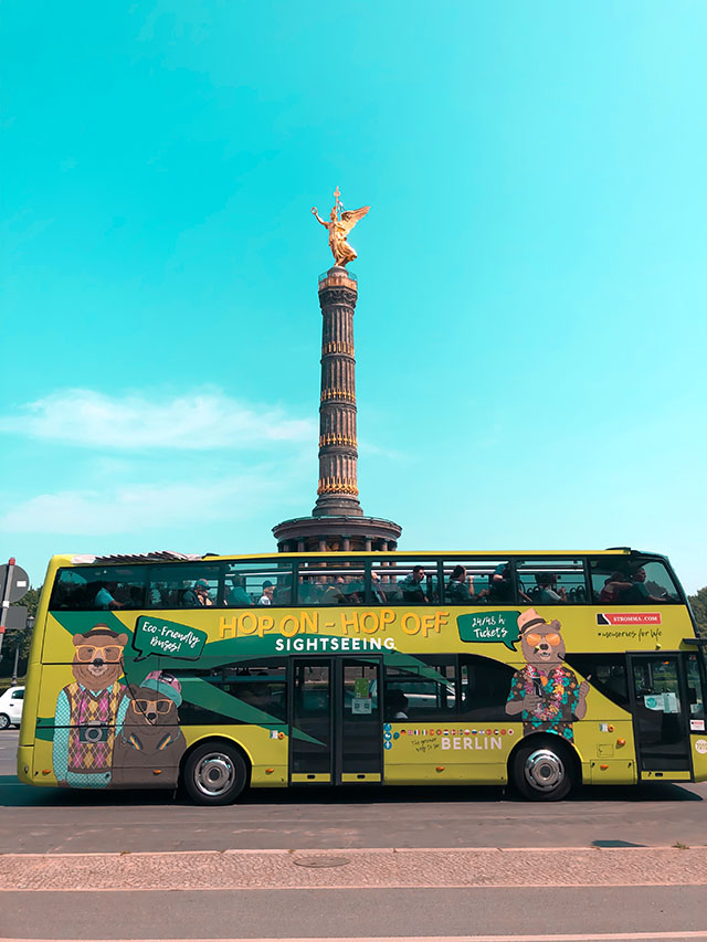 the berlin hop on hop off tour bus with the victory column at großer stern in the backdrop in berlin germany
