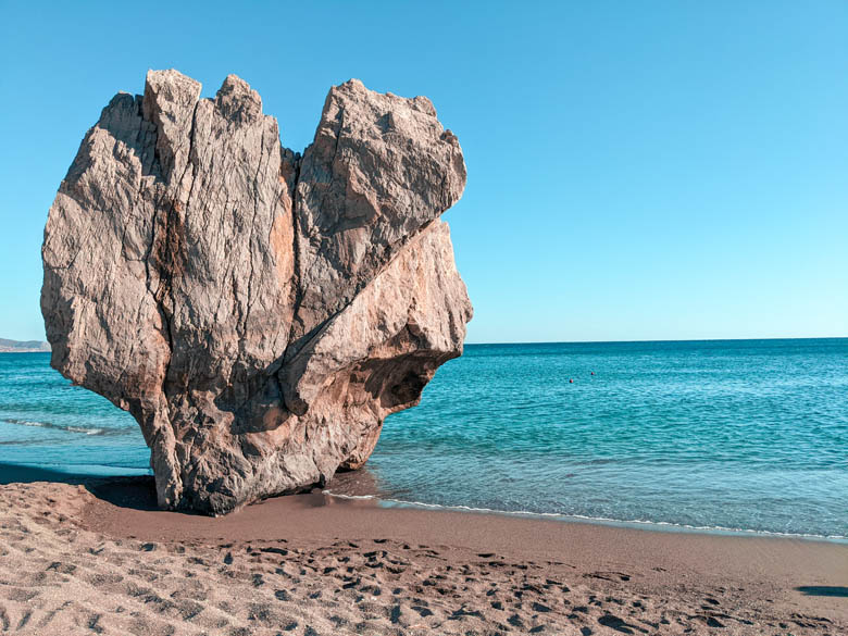 a giant heart shaped rock standing upright on preveli beach in crete