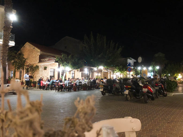 a view of hersonissos old town village at night with people eating at restaurants