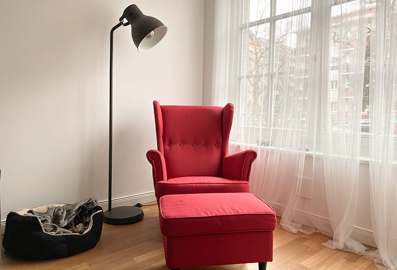 a standing lamp used for task lighting standing next to a red armchair in an apartment in berlin