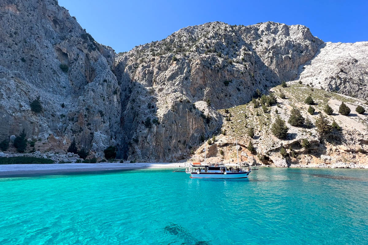 a view of saint george bay at symi island with a backdrop of mountains and a boat floating on the water