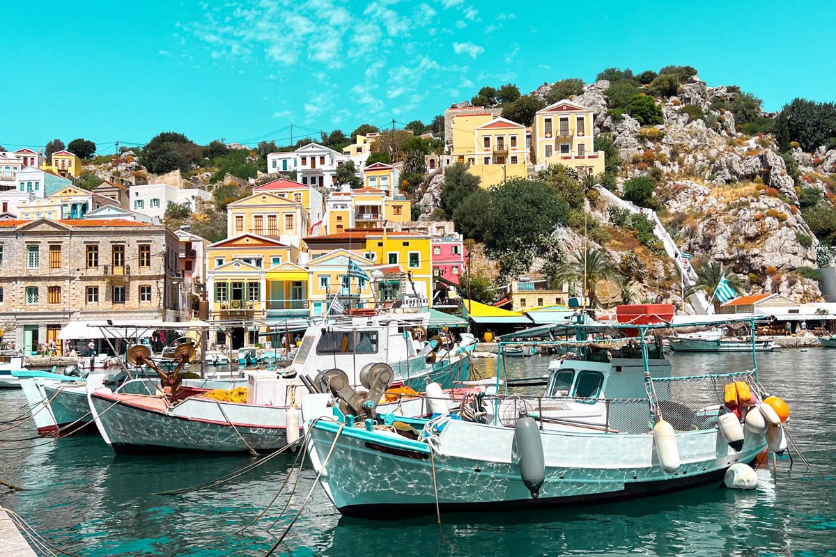 white boats sitting in the water with colorful neoclassical buildings on the mountains in the background