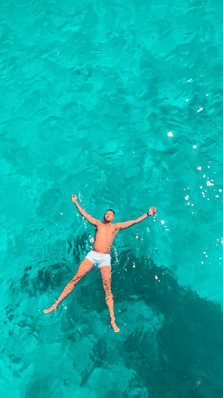 a man floating on electric azure blue water at saint george bay simi island