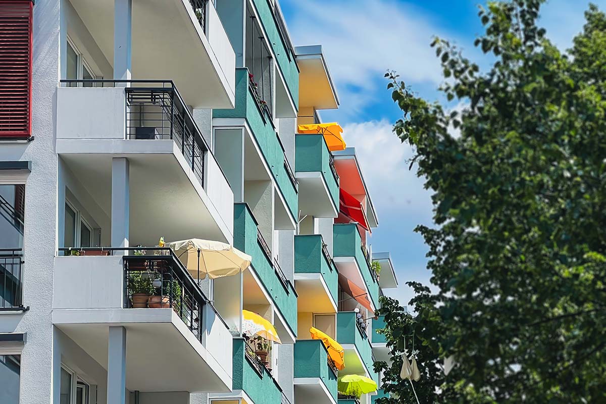 an apartment building in germany with colorfully painted balconies and yellow umbrellas