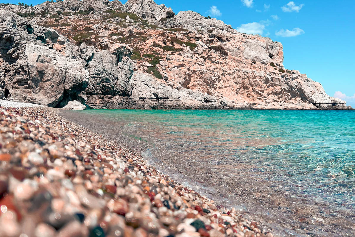 colorful pebbles on traganou beach with white cliffs in the background