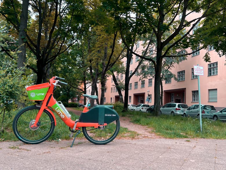 uber lime red e-bike parked on the pavement with trees in the background