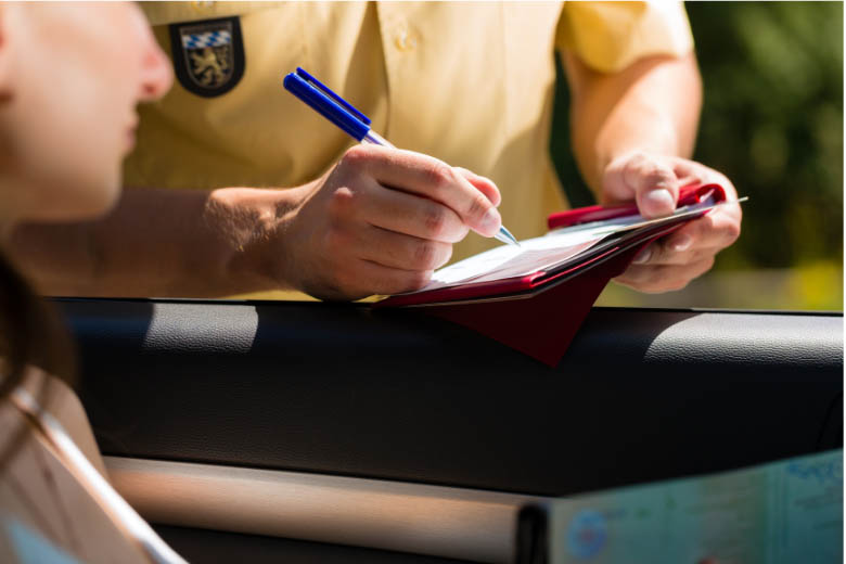 a traffic official issuing a speeding ticket to a driver seated in a vehicle