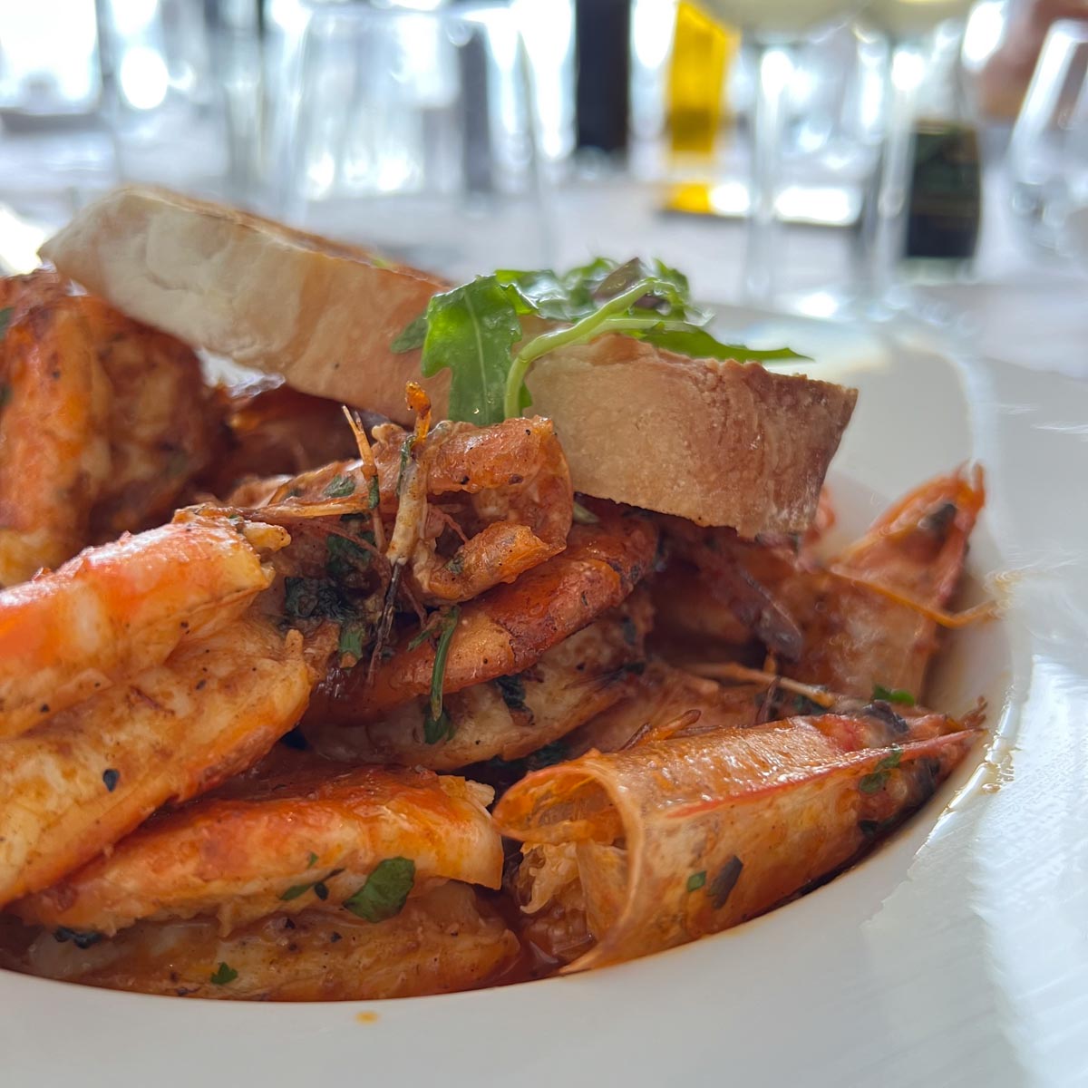 locals eat grilled king prawns with a slice of bread on top in kalk bay cape town