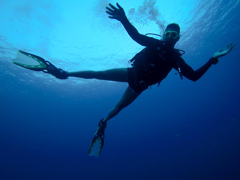 a man scuba diving with his arms and legs spread out 