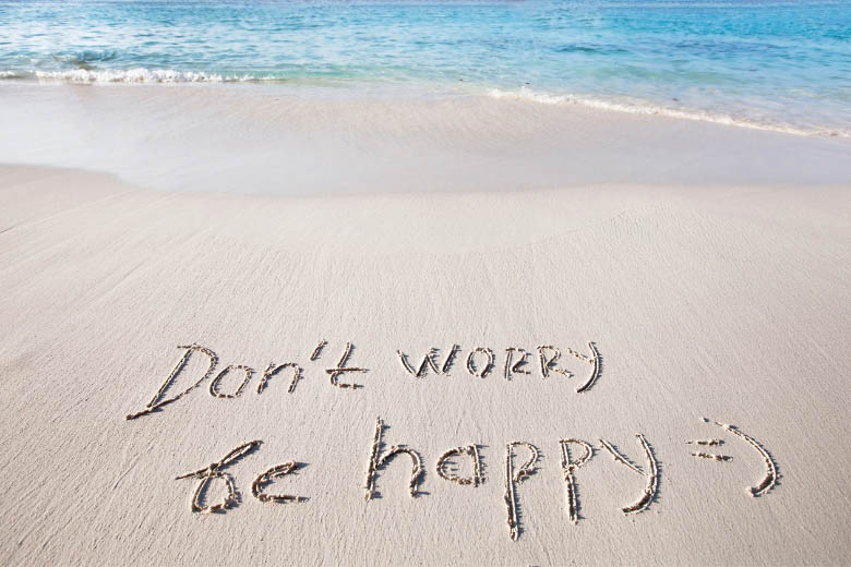 words drawn on the sand at a beach that says don't worry be happy