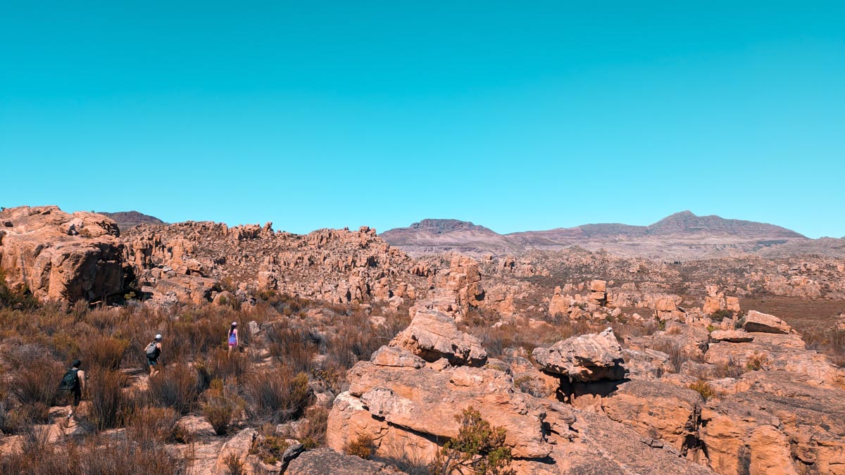 hikers walking between reddish cliffs and rocks in the cederberg mountains south africa