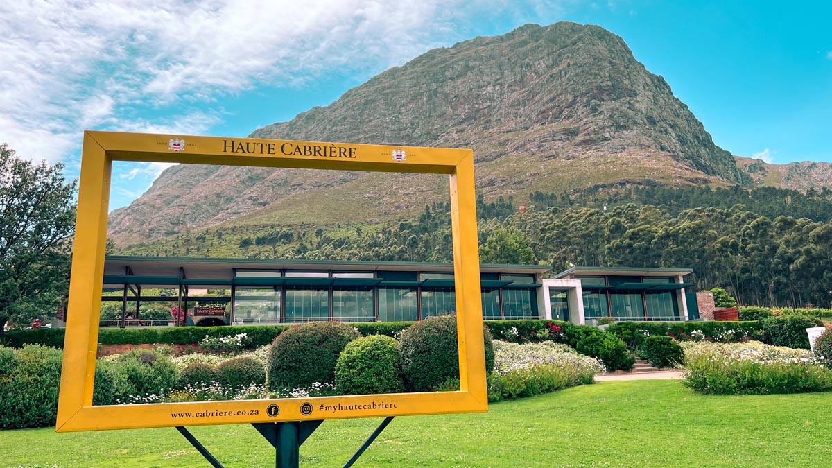 a view of haute cabriere winery in franschhoek with a discover cape town yellow photo frame 