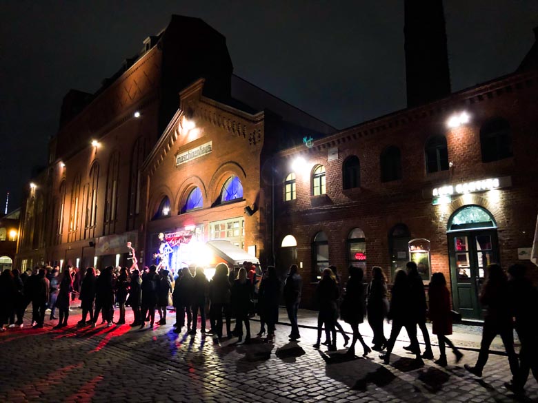 a long queue of people standing in a line to go inside a nightclub in berlin