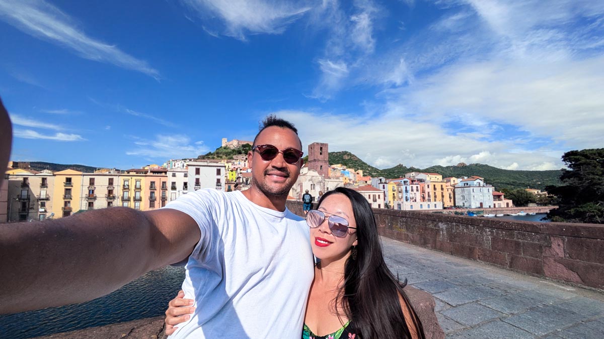 a couple taking a selfie in front of colour houses and buildings in bosa north west sardinia