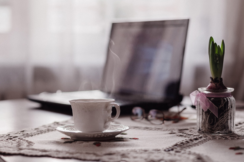 a white tea cup on a desk with a laptop in the background