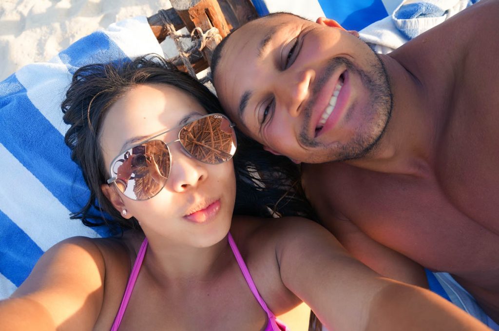 a couple lying on sunbeds smiling into the camera at the doubletree by hilton zanzibar hotel on the beach